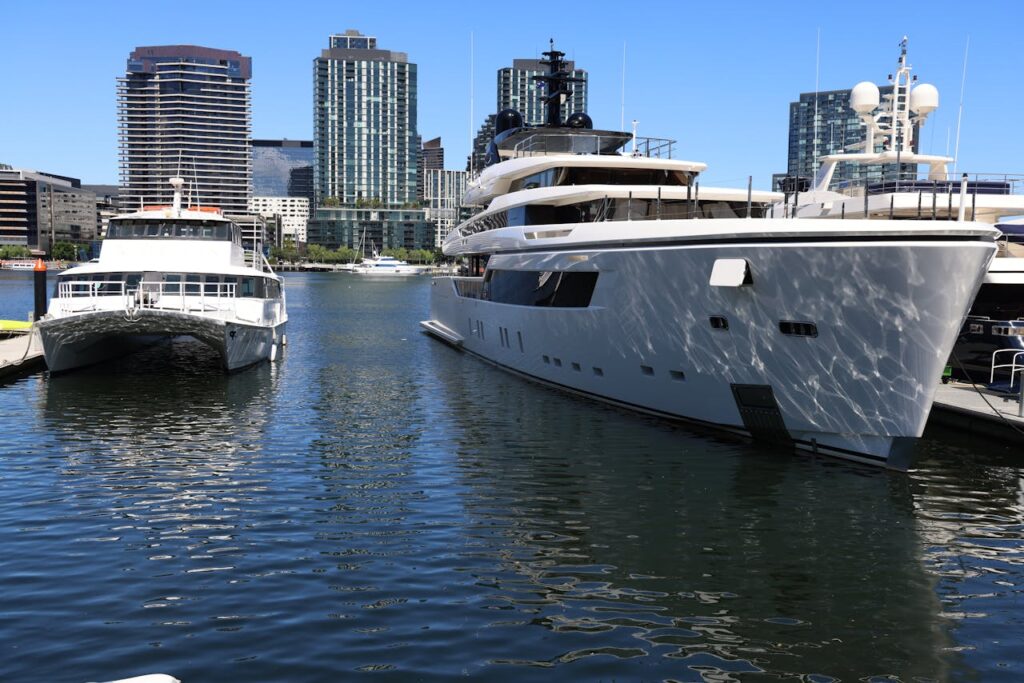Large luxury yachts docked at a city marina with skyscrapers in the background.